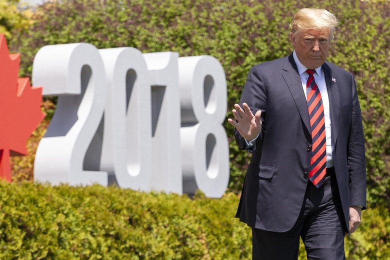 Donald Trump walks by a sign that says 2018 with a red maple leaf.