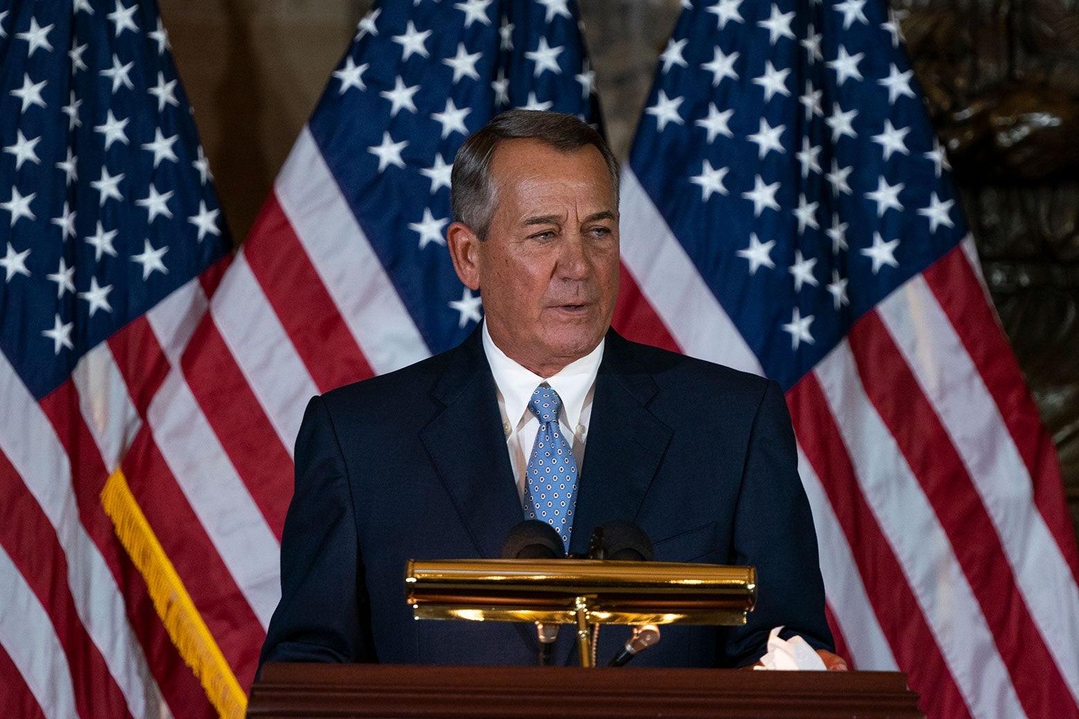 Boehner speaks at a podium with American flags behind him