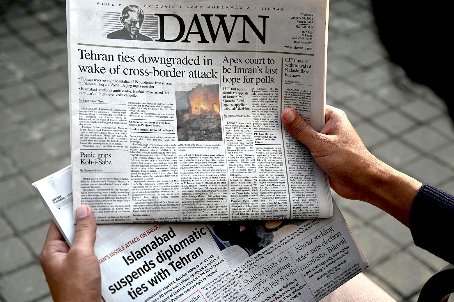 A man reads the front page of the Pakistani English-language newspaper Dawn displaying news on Iran’s airstrike, in Islamabad on Thursday. The headline reads "Iran ties downgraded in wake of cross-border attack."