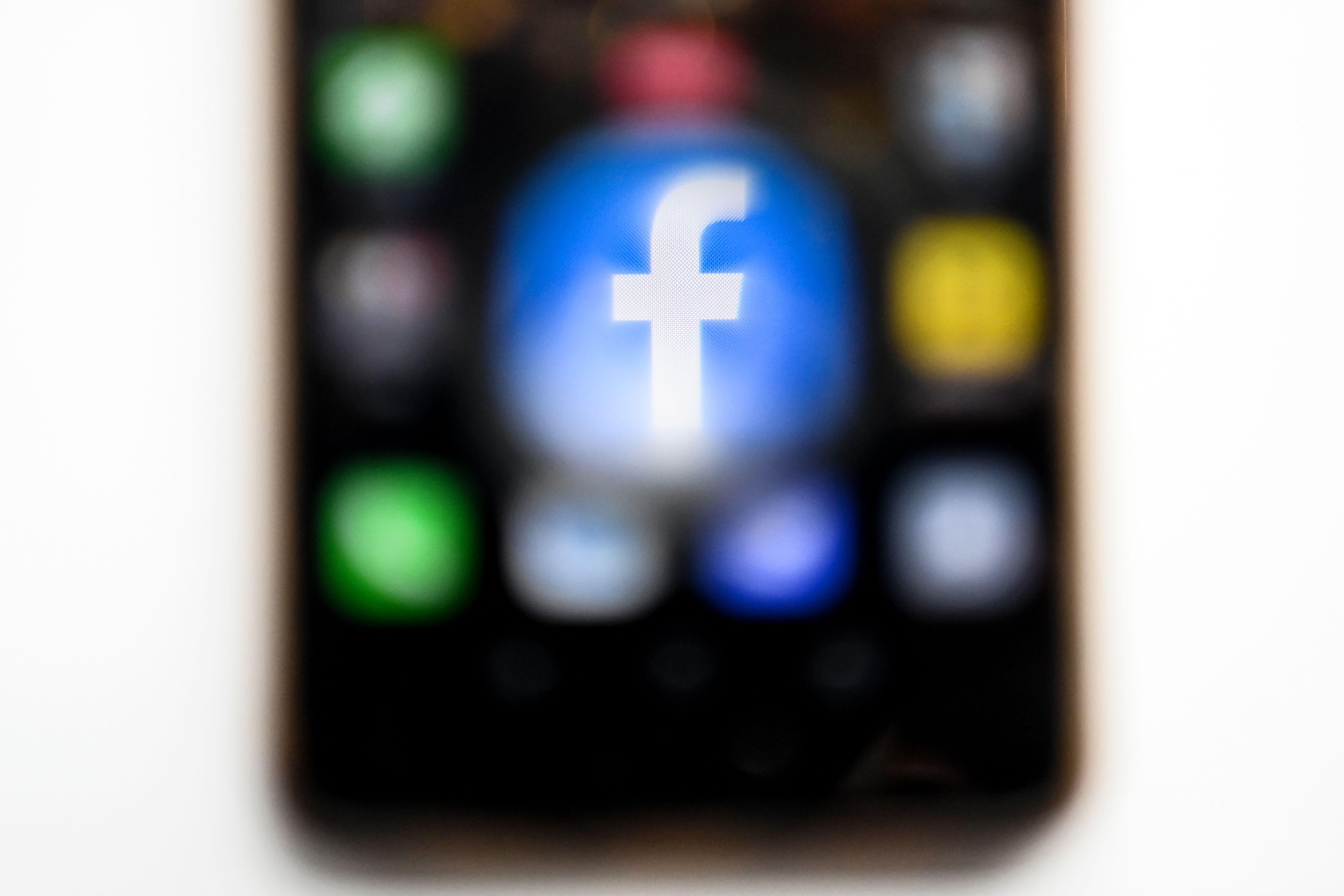 A blurry image of a smartphone home screen, with a large Facebook icon.