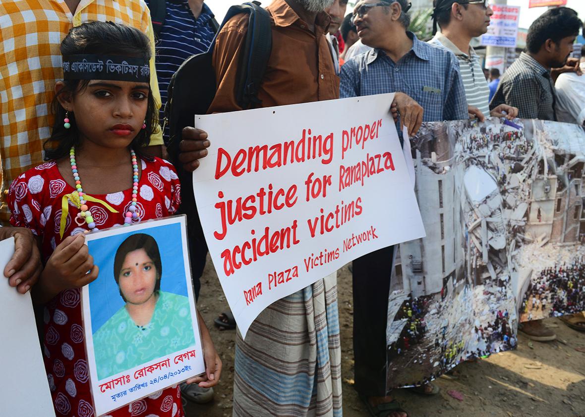 A Bangladeshi girl holds a photo of her mother, who died in the Rana Plaza building collapse, during a protest march on the third anniversary of the disaster at the site where the building once stood in Savar, on the outskirts of Dhaka on April 24, 2016.