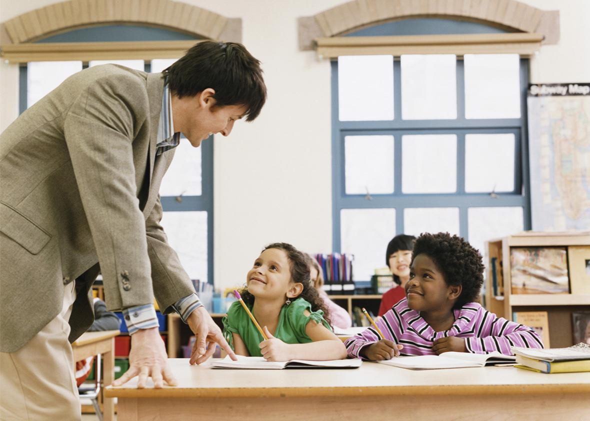 Male Teacher in a Classroom Helping Primary School Children