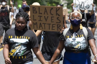 Two demonstrators hold hands amid a Black Lives Matter march