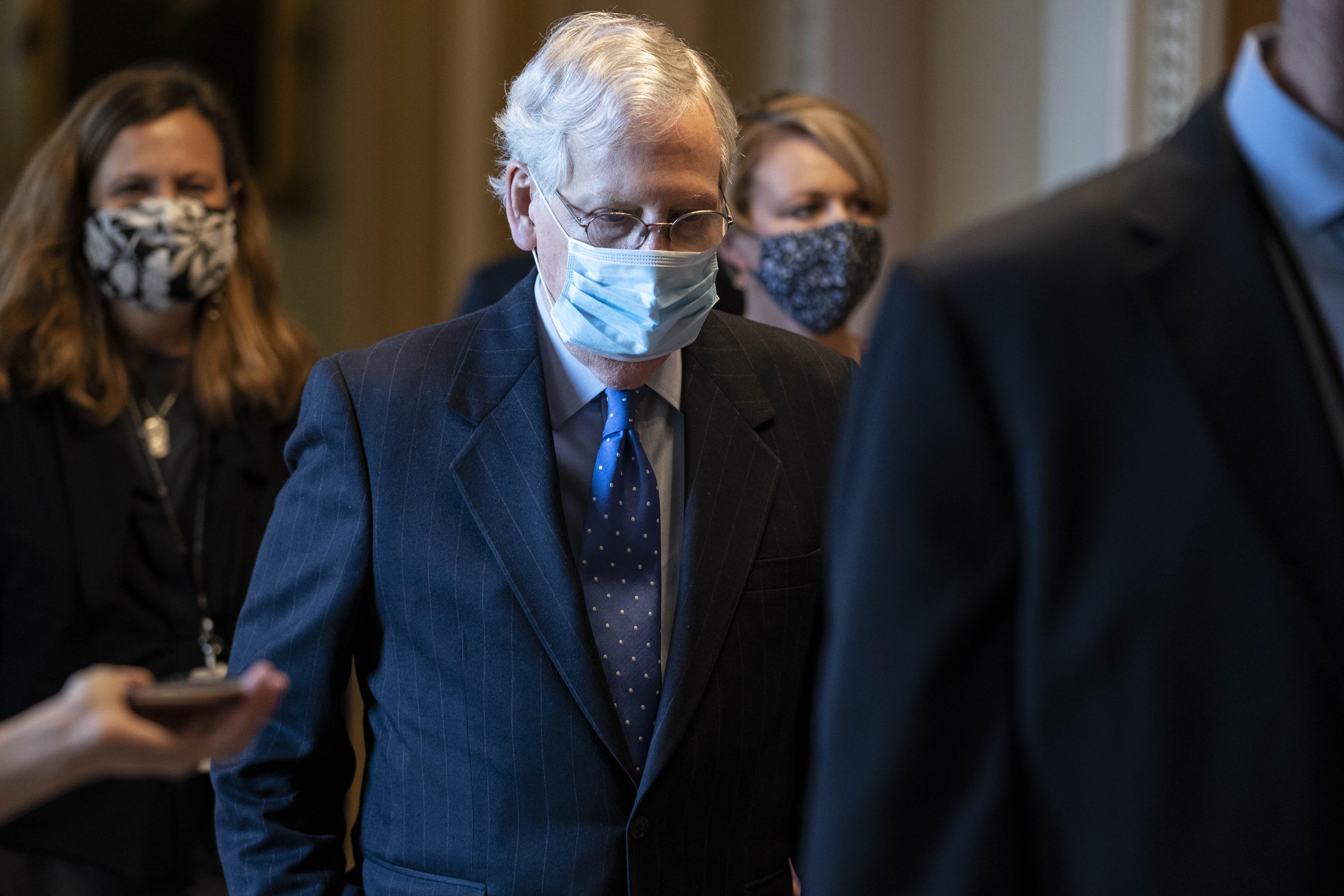 McConnell, wearing a mask, walks in a hallway