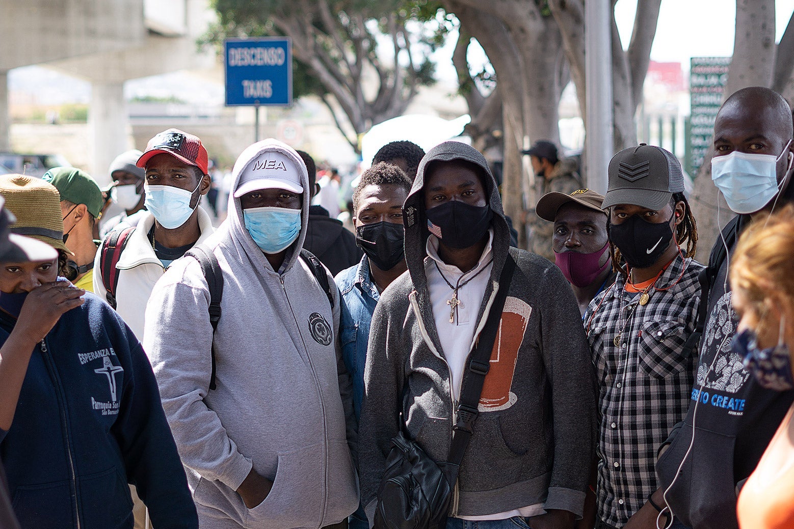 A group of men stand together wearing masks.