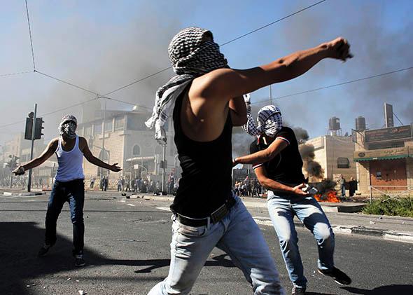 Palestinians hurl stones during clashes with Israeli police in Shuafat, an Arab suburb of Jerusalem, on July 2, 2014.