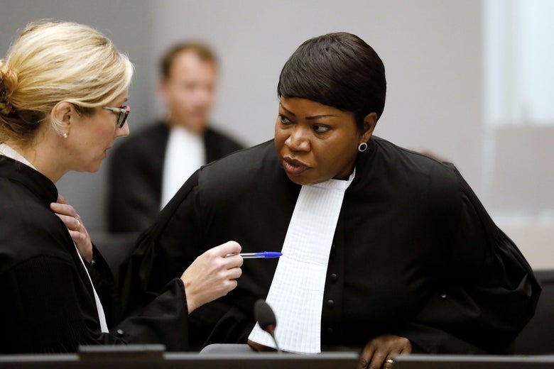Fatou Bensouda speaks to a woman who is gesticulating with a pen near a microphone.