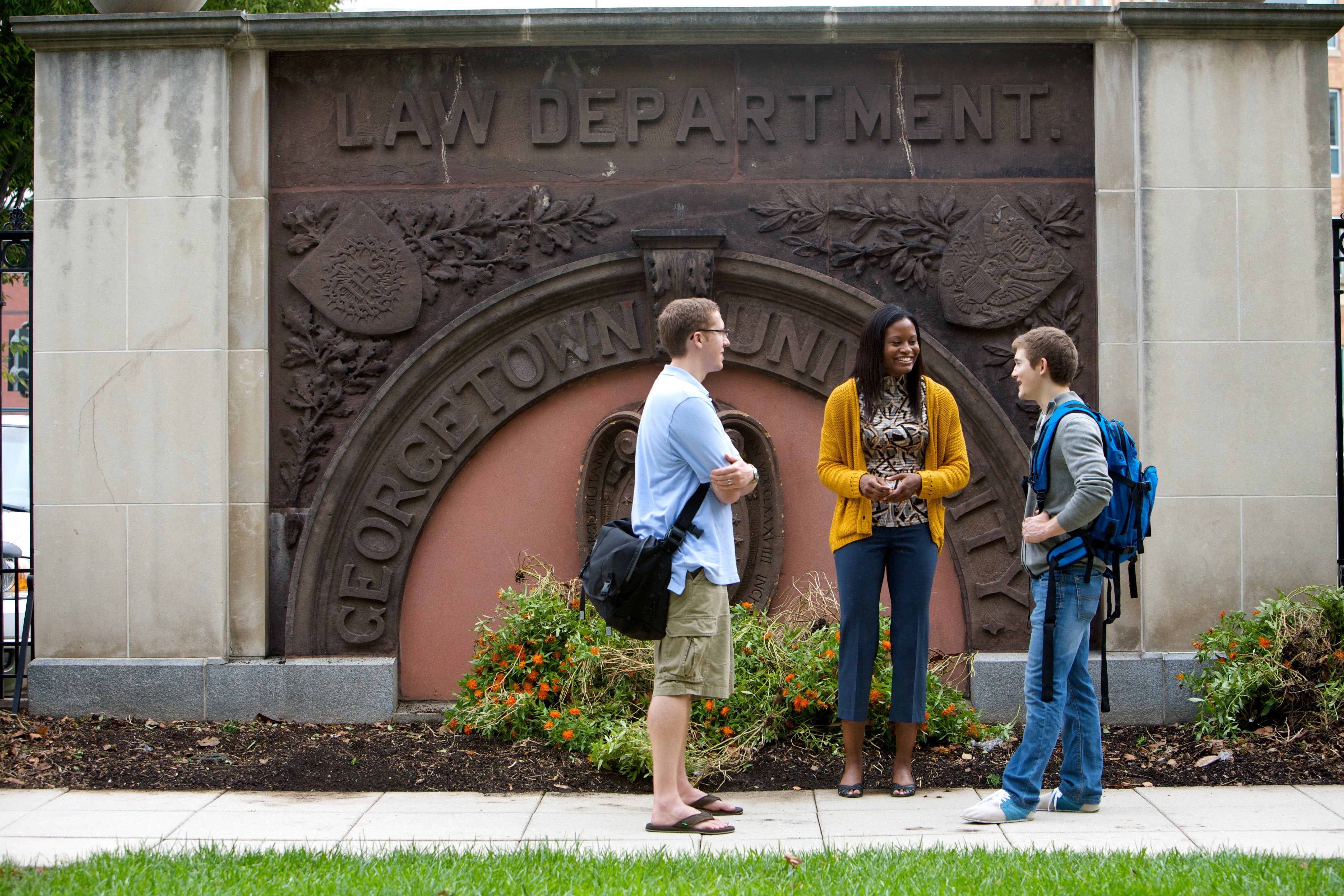 Three students chat on a campus. 