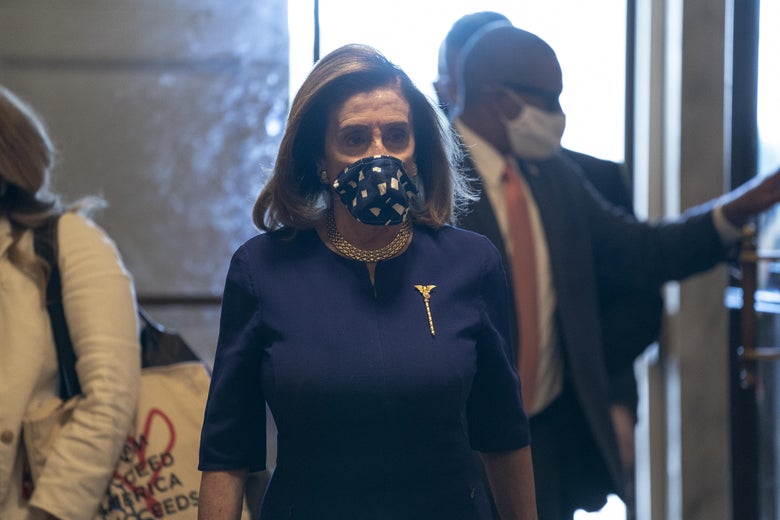Pelosi wearing a blue mask walks through Congress.