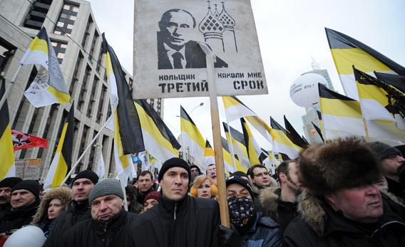 Protesters, activists of nationalist groups, hold the Russian Empire's black-yellow-white flags and a poster depicting Russia's Prime Minister Vladimir Putin.