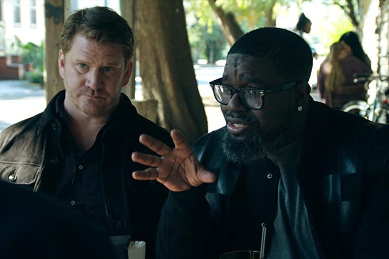 Two men are sitting at a lunch table, and one of them is talking and gesturing with his hands.