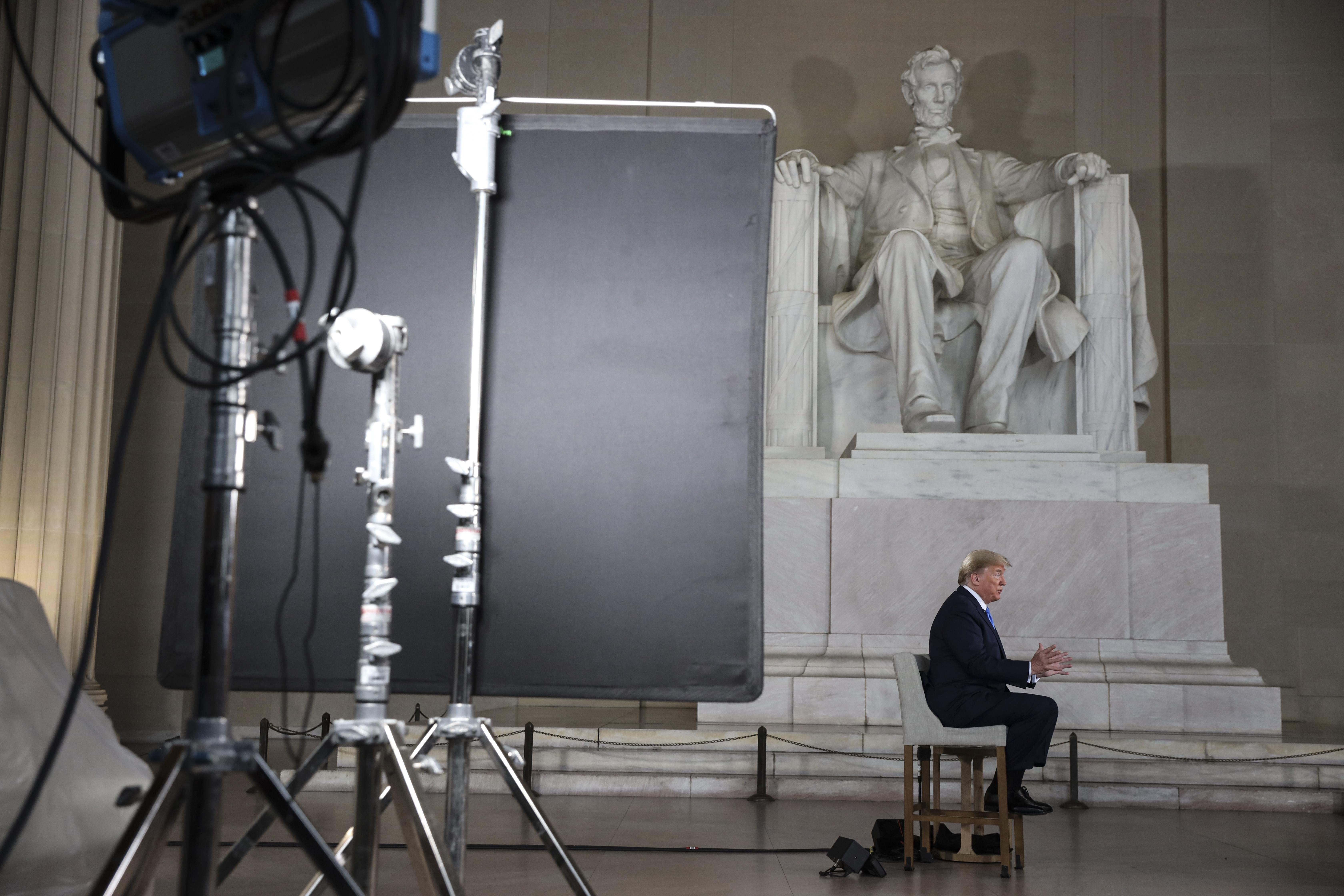 A wide shot of President Donald Trump seated, doing a Fox News town hall in front of the Lincoln Memorial.