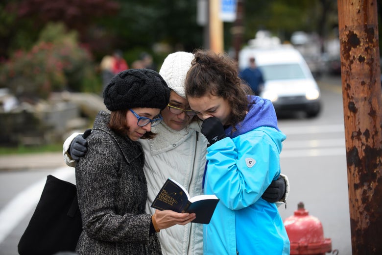 Tammy Hepps, Kate Rothstein and her daughter, Simone Rothstein, 16, pray from a prayerbook a block away from the site of a mass shooting at the Tree of Life Synagogue in the Squirrel Hill neighborhood on October 27, 2018 in Pittsburgh, Pennsylvania.