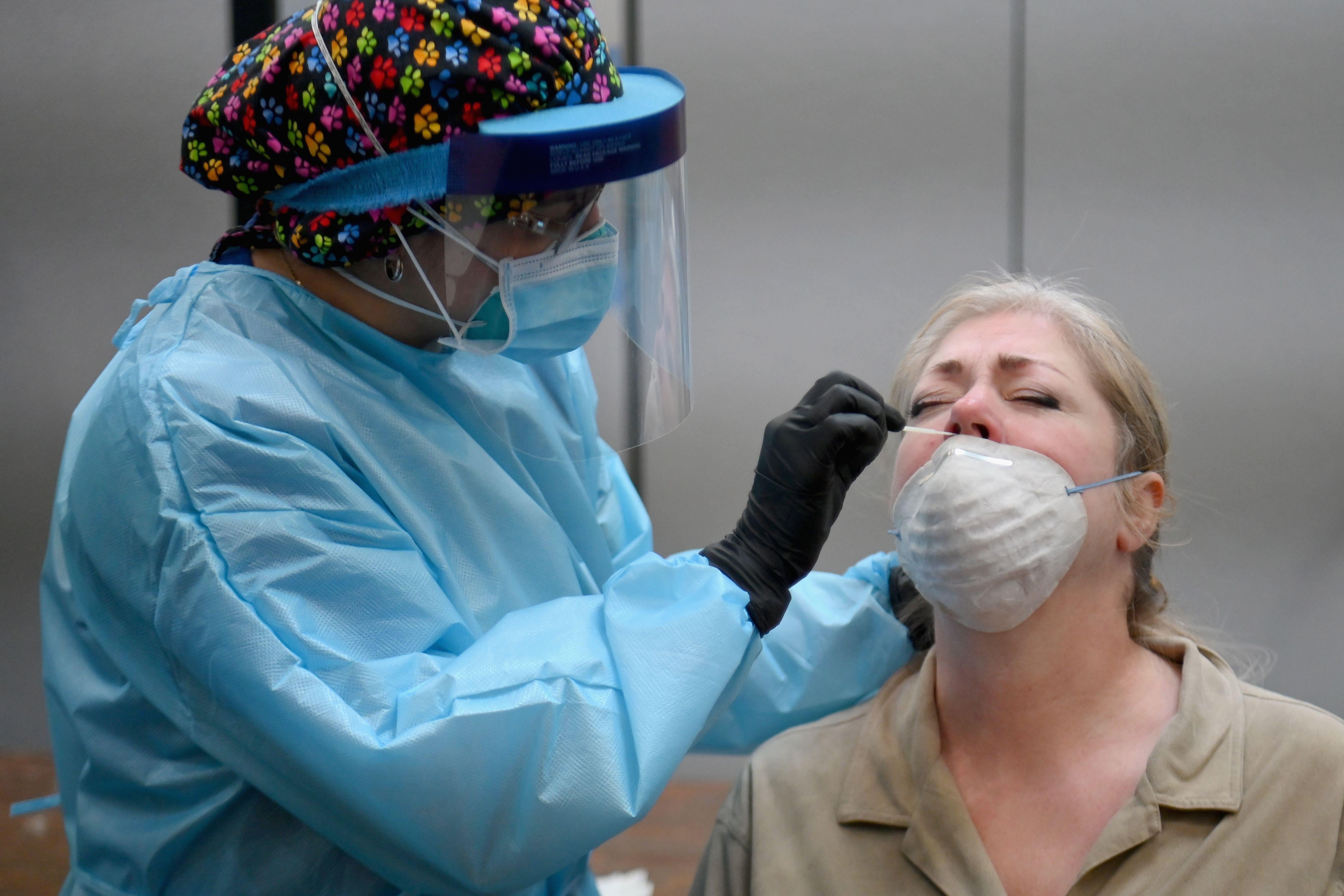 A health care worker puts a nasal swab up a woman's nose 