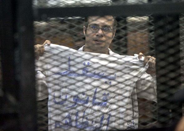 Political activist and coordinator of the April 6 Movement, Ahmed Maher shows a T-shirt reading "Dropping the law on demonstrations" during his trial over an unlicensed and violent demonstration on December 8, 2013 in Cairo, Egypt. 