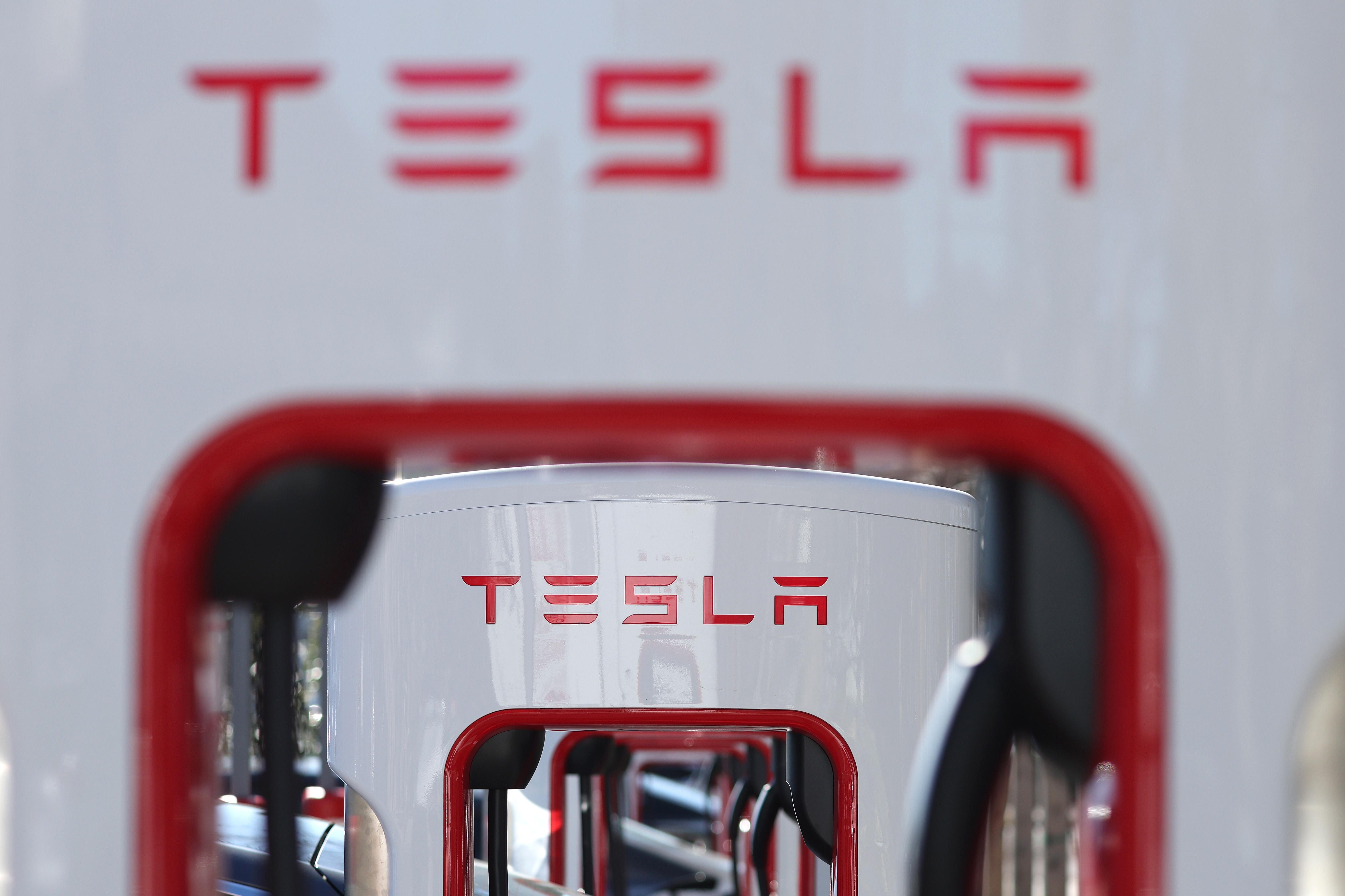A row of white Telsa chargers that say "Tesla" in red letters. 