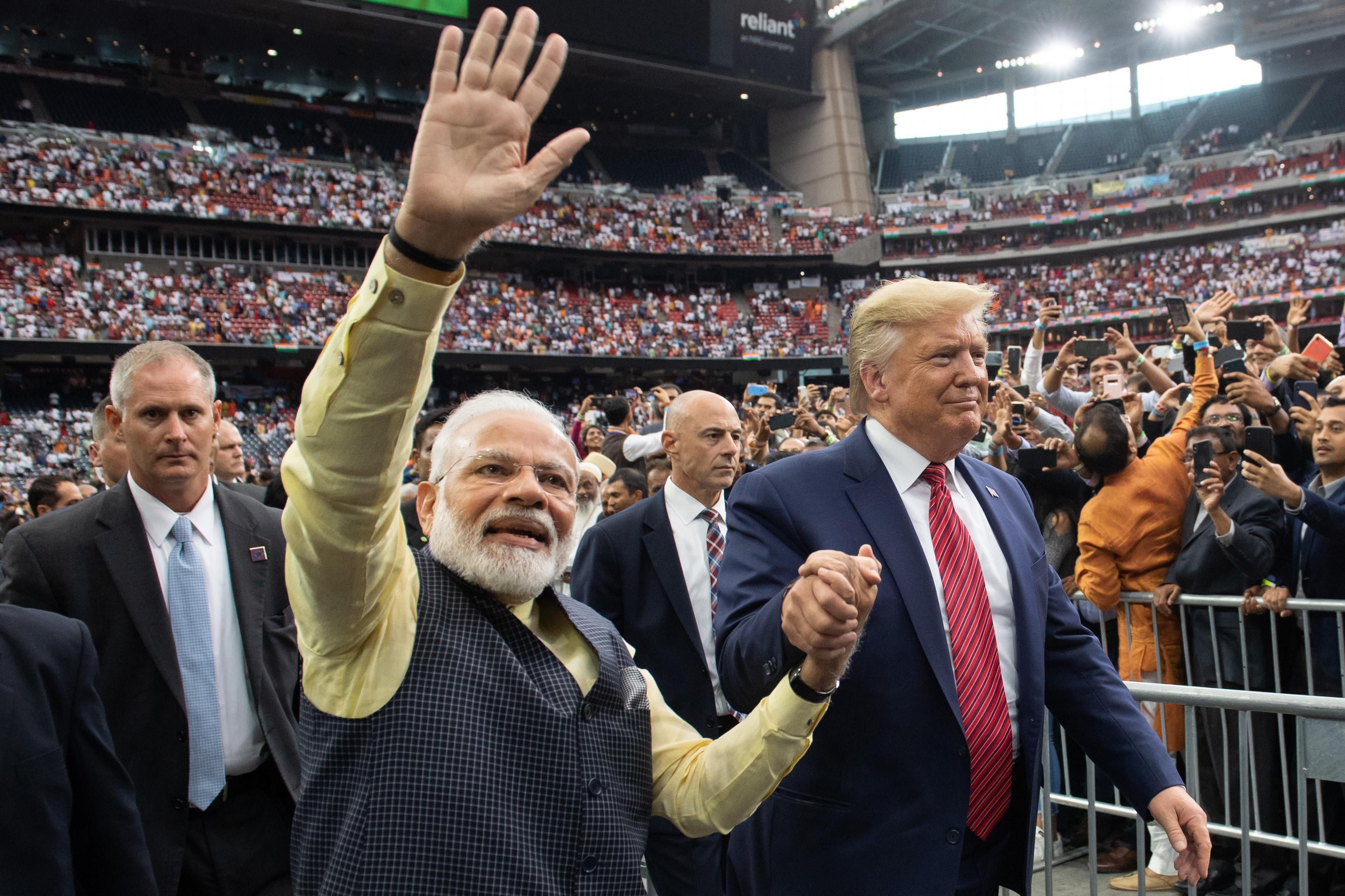 Modi and Trump hold hands as Modi waves at the crowd.