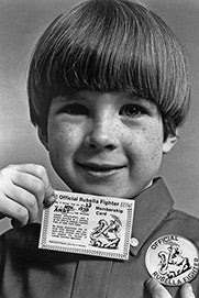 A kid carries an "Official Rubella Fighter" card and wears a button with the same phrase.