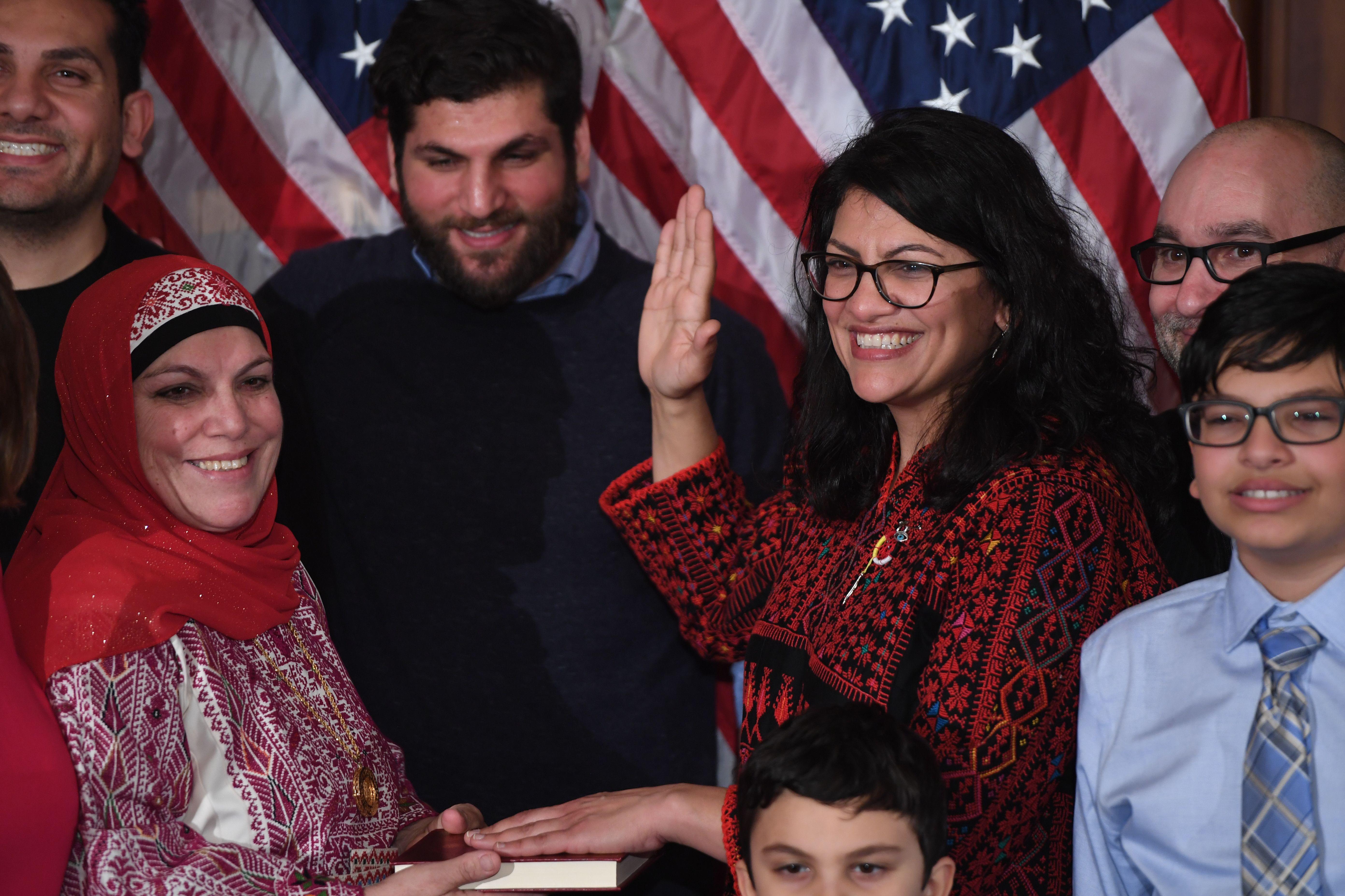 Rashida Tlaib, surrounded by family members, raises her hand to take the oath of office.