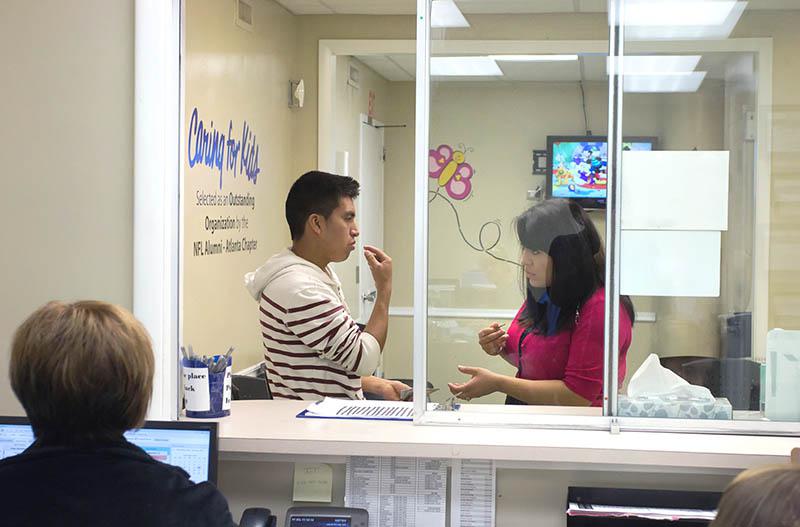 Yessi Navarro assisting a Spanish speaking patient in the patient waiting area.