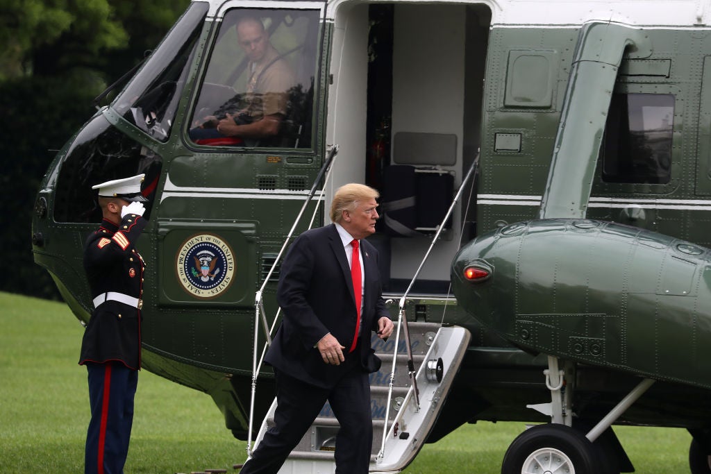 Trump walks away from a presidential helicopter as a Marine salutes.