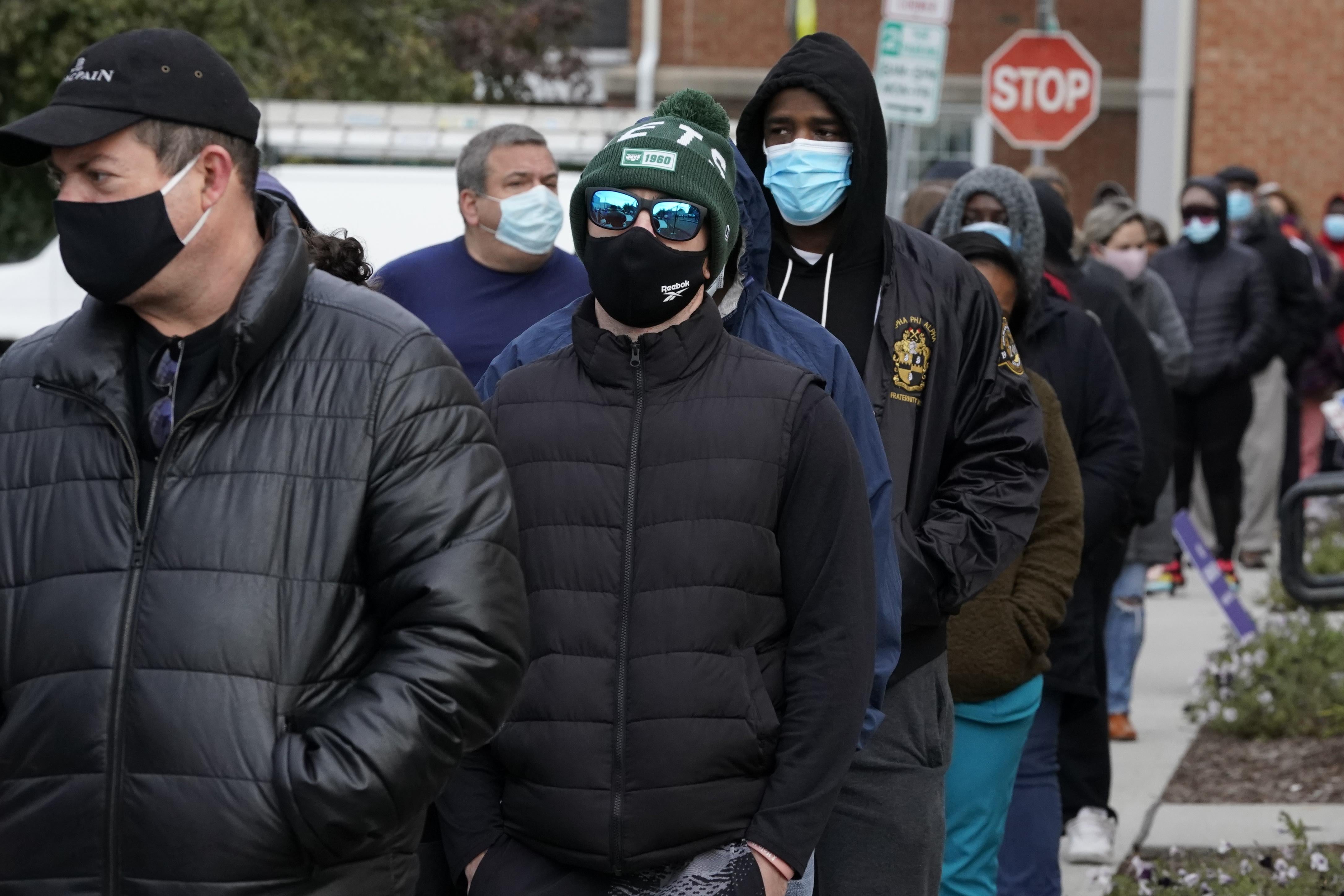 A line of people in winter clothes and face masks.