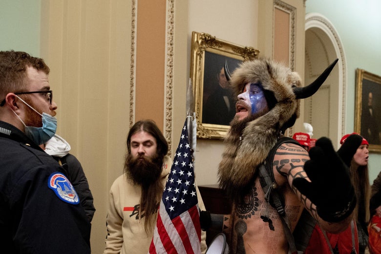 Supporters of President Donald Trump, including Jake Angeli, a QAnon supporter known for his painted face and horned hat, protest in the US Capitol on January 6, 2021, in Washington, D.C.
