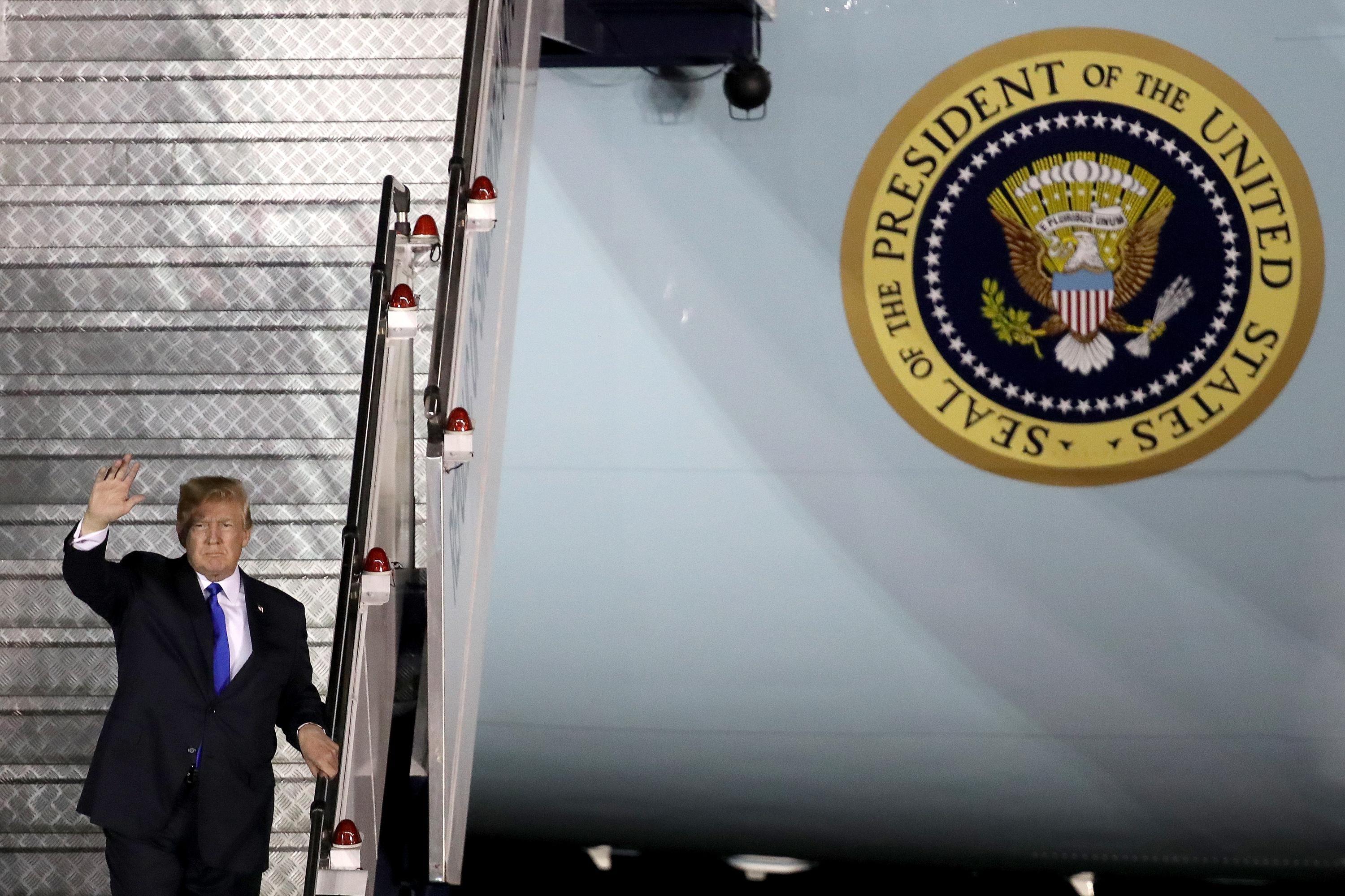 Donald Trump waves as he descends the stairs down from Air Force One.