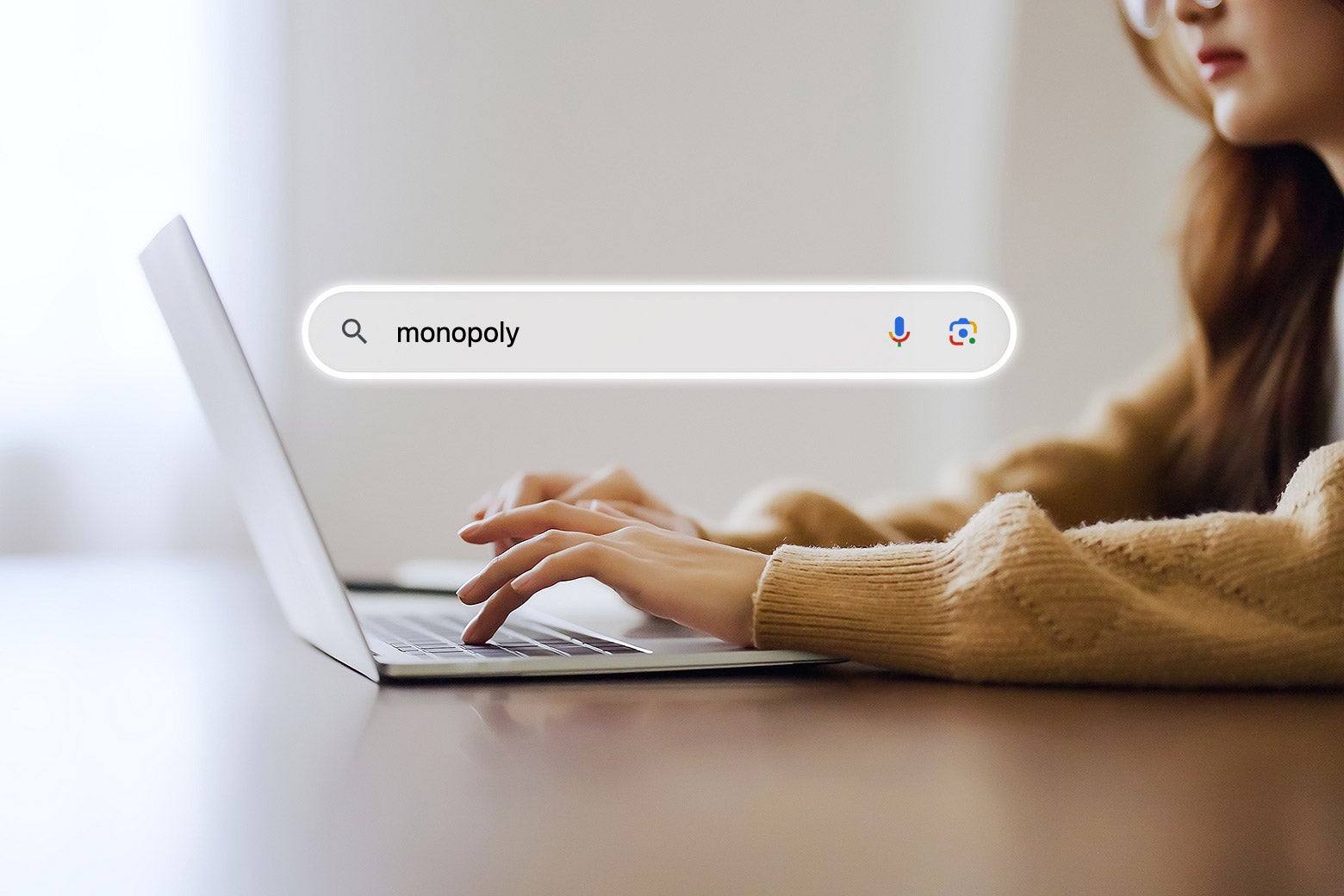 A woman typing the word "monopoly" into a Google search bar.