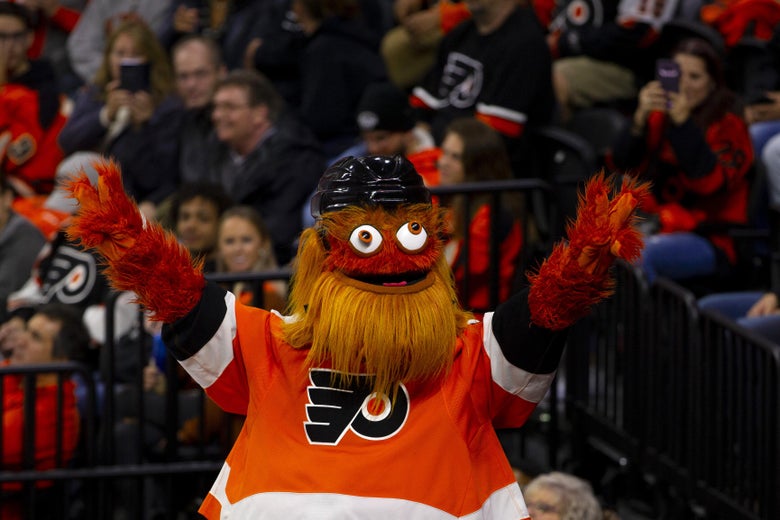 Philadelphia Flyers mascot Gritty holds up two peace signs during a hockey game.