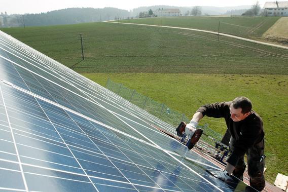 A worker mounts 320 square metres of solar panels on the roof of a farmstead barn in Binsham near Landshut March 21, 2012. 