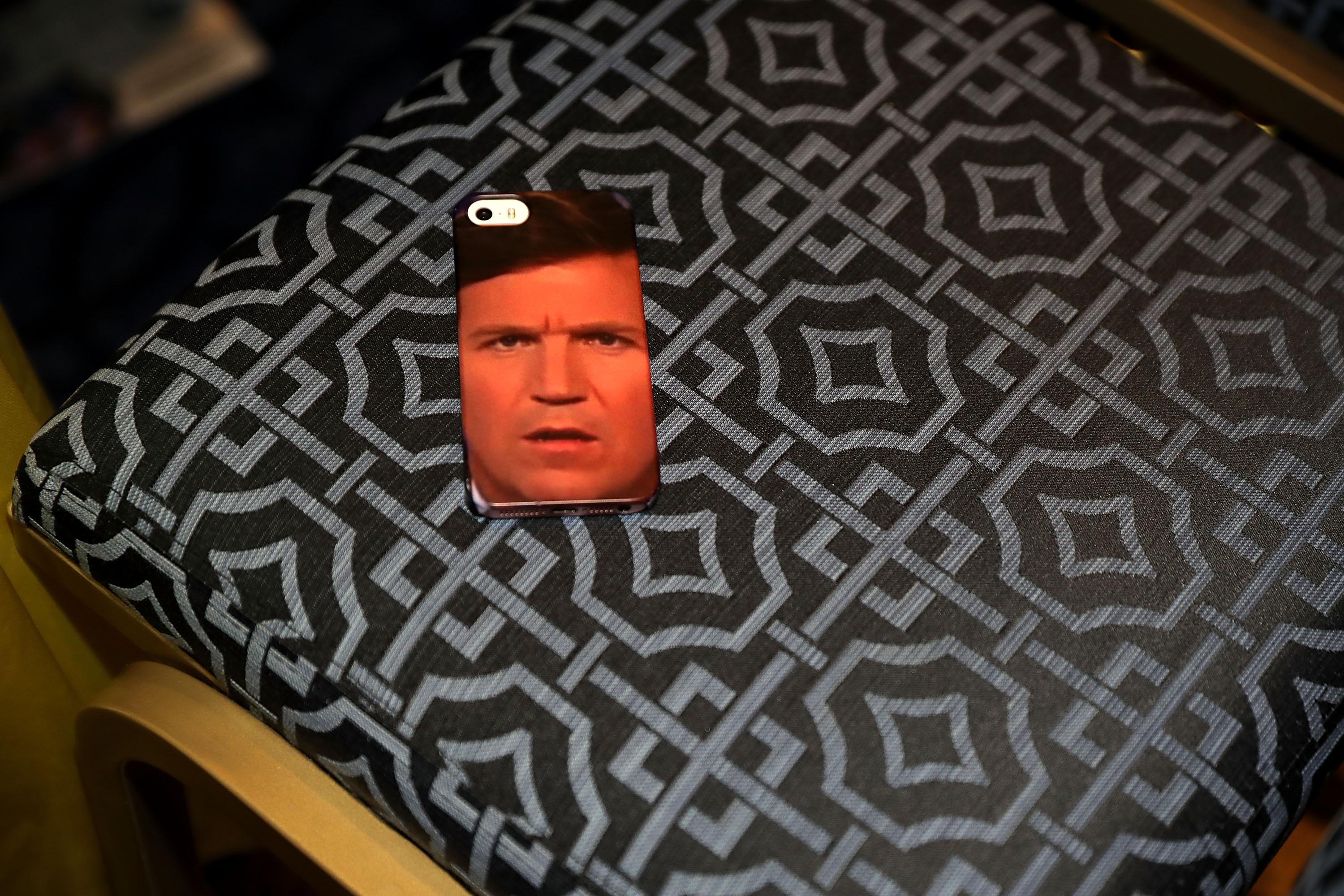 An iPhone case with Tucker Carlson's face is left in a chair.