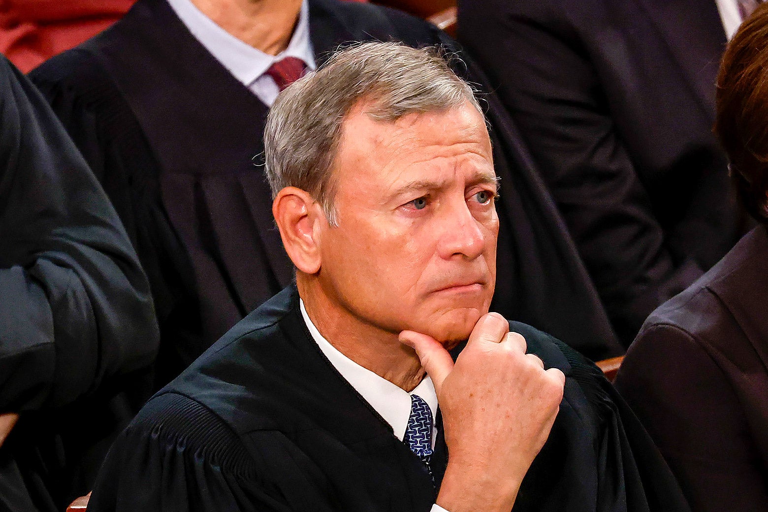 John Roberts holds his hand to his chin.