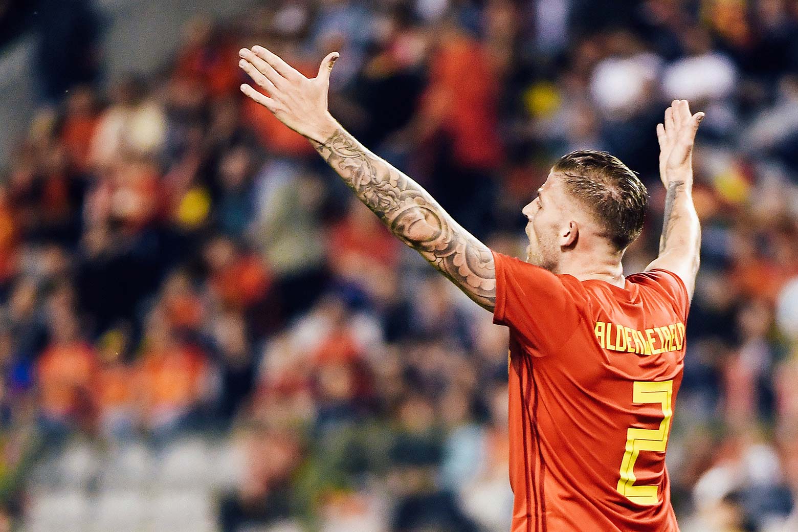 Toby Alderweireld holds up his tattooed arms while on the field.
