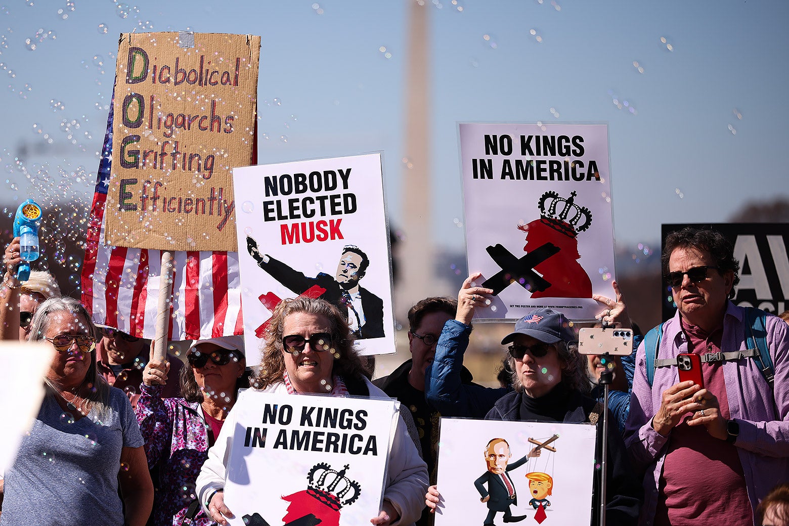 Protestors hold signs criticizing Donald Trump and Elon Musk during a Shut Down the Coup protest in Washington D.C.