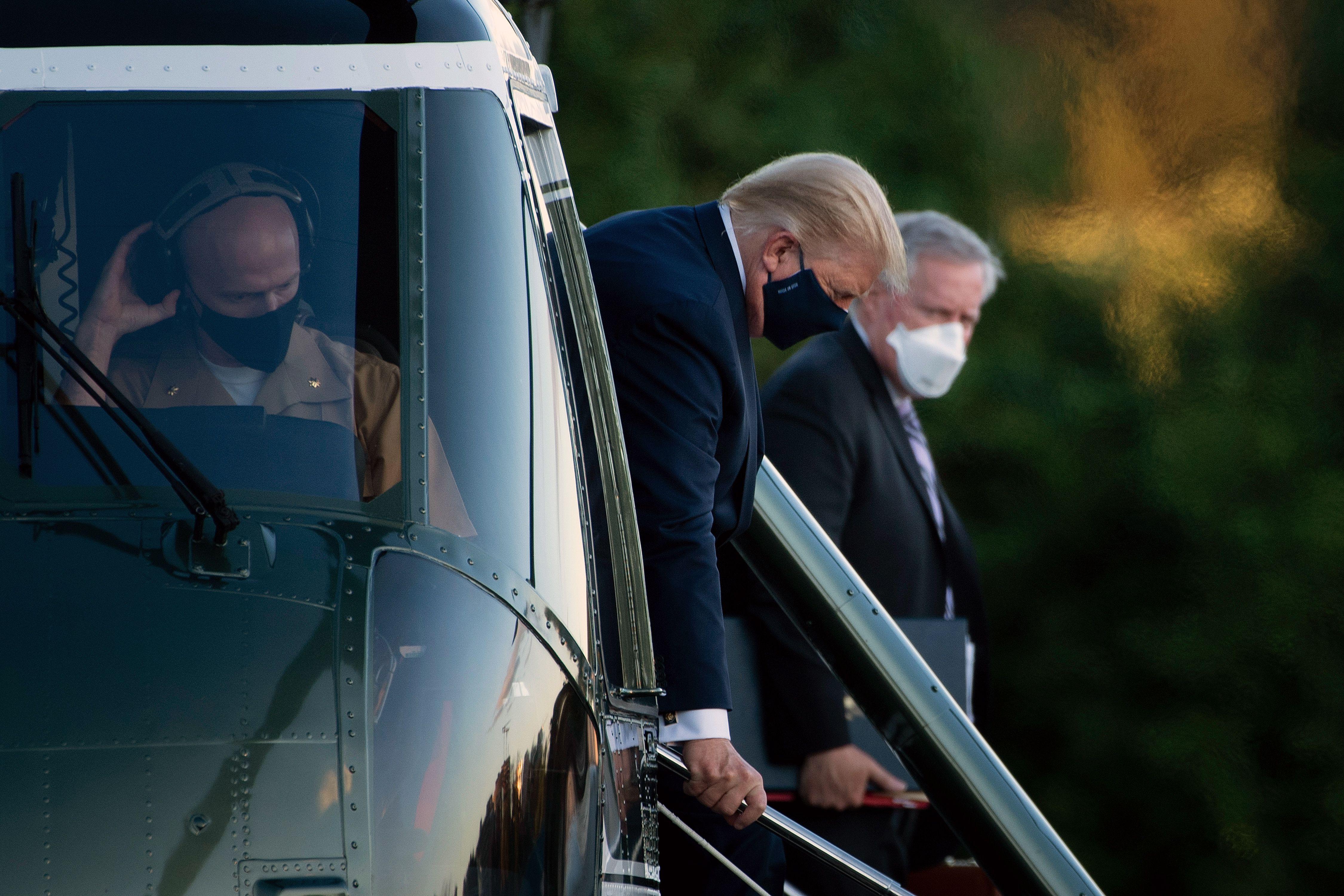 Trump and Mark Meadows, both wearing masks, step off a helicopter.