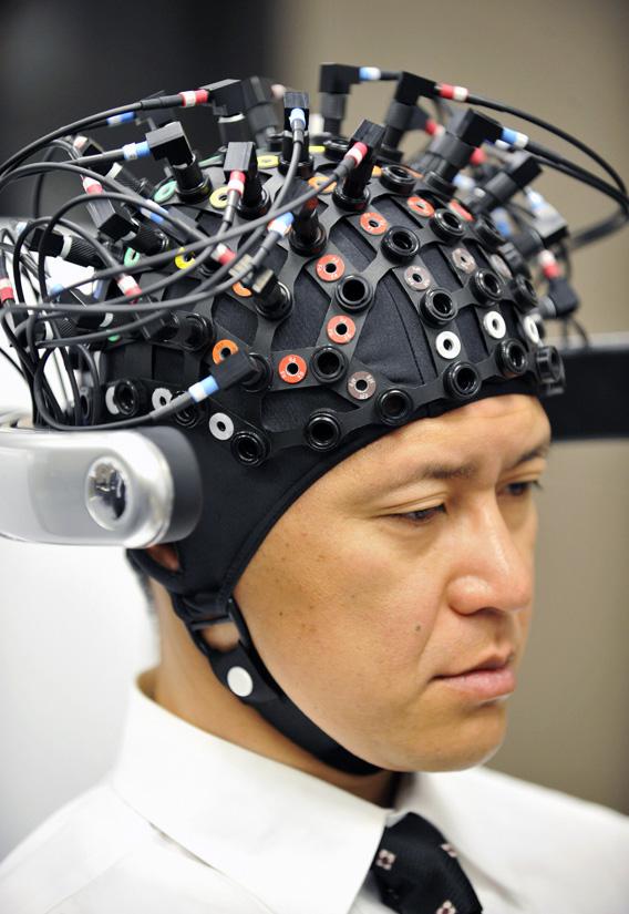 A man wears a brain-machine interface, equipped with electroencephalography (EEG) devices and near-infrared spectroscope (NIRS) optical sensors in a special headgear to measure slight electrical current and blood flow change occuring in the brain.