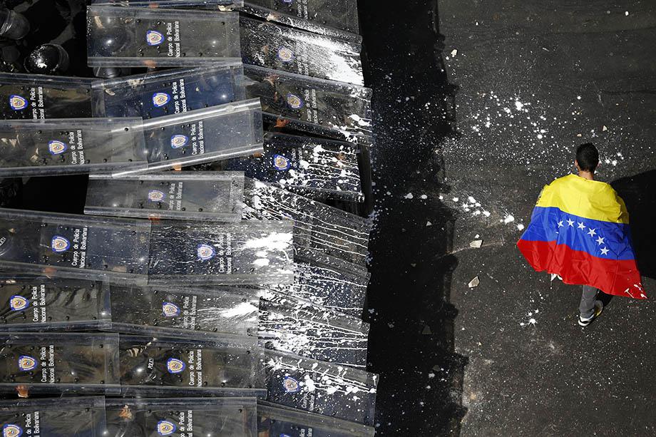 A demonstrator with a Venezuelan flag draped around himself protests against the government of Venezuela's President Nicolas Maduro.