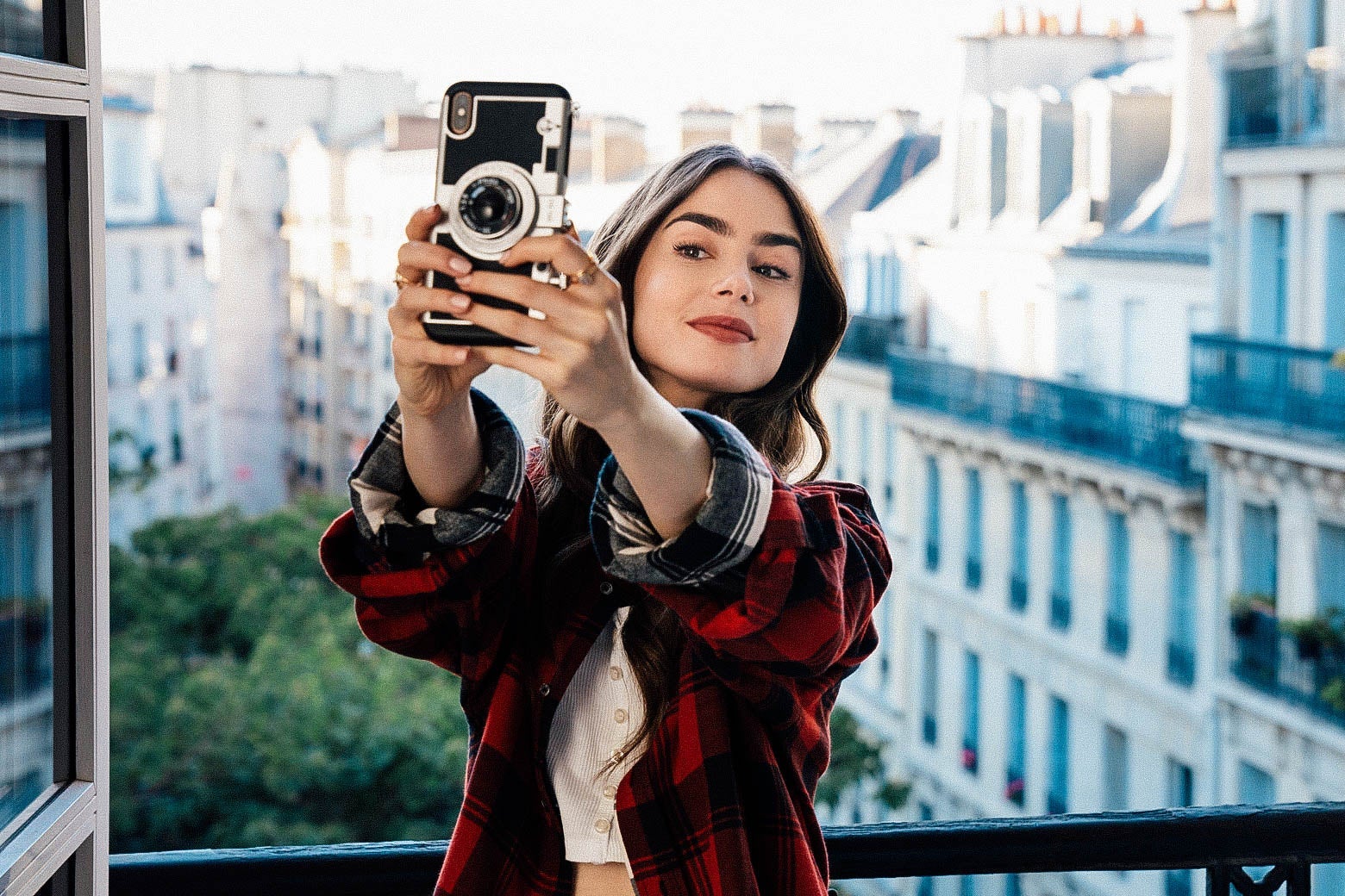A young brunette takes a selfie on a Parisian balcony.