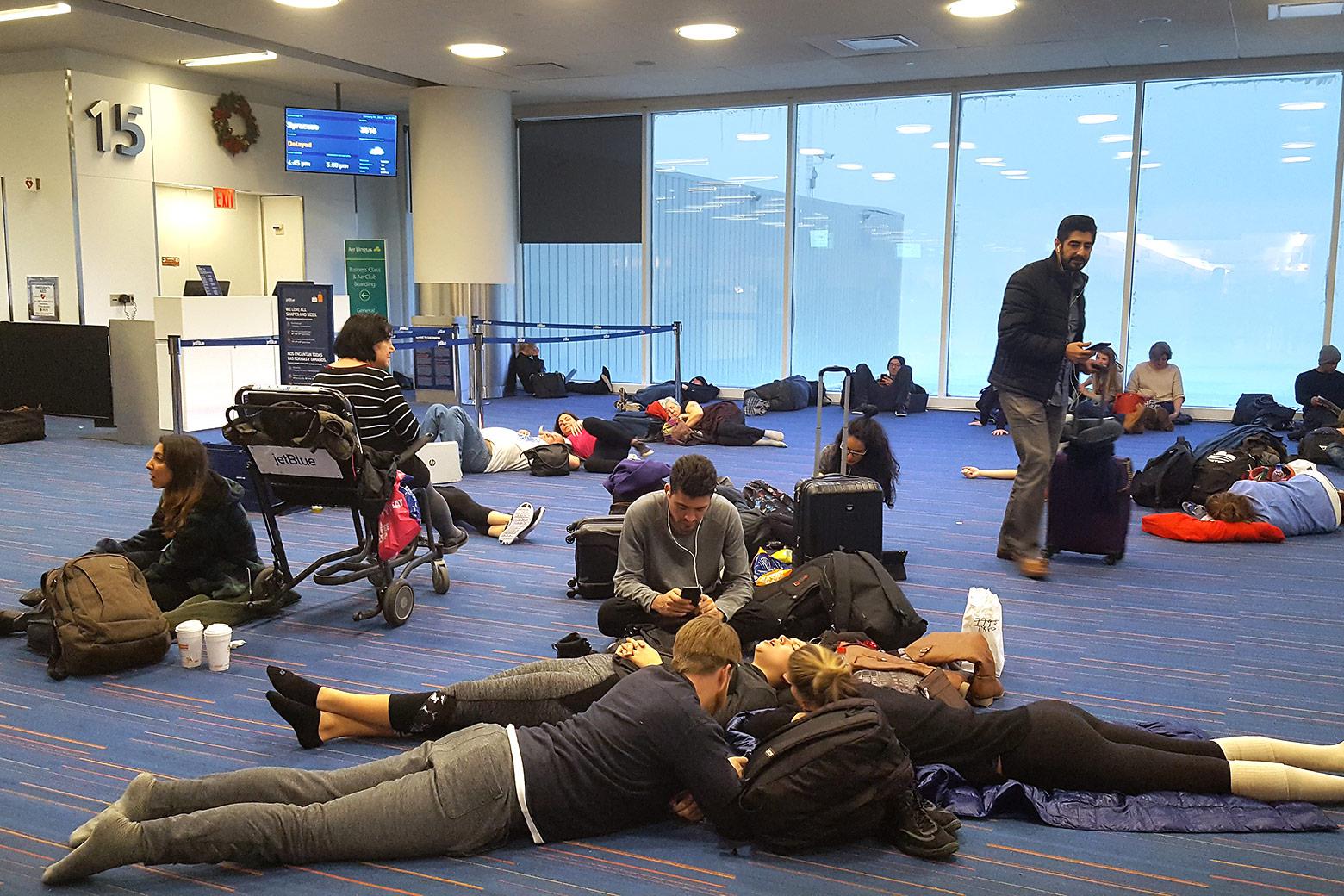 Passengers sit and lay on the floor of the airport.