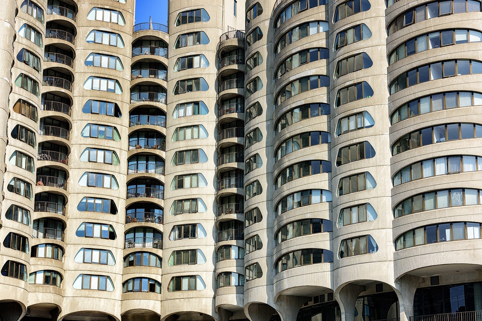 Tan-colored Brutalist apartment complex of cylindrical towers with window cutouts on each floor shaped like coin slots