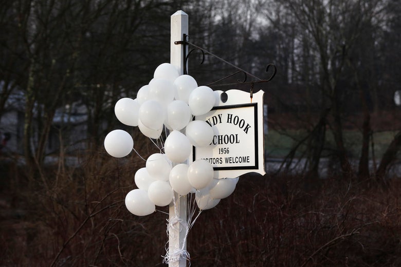 White balloons hang from the Sandy Hook School sign