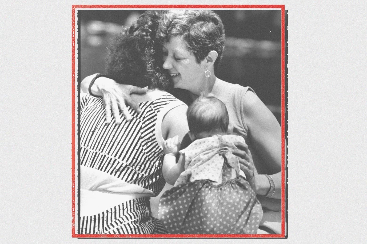 Photo of McCorvey smiling and embracing a woman and a baby in a red frame