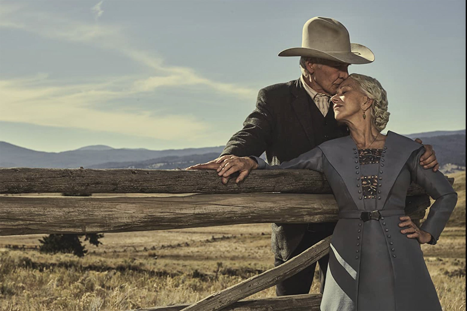 Harrison Ford and Helen Mirren as their 1923 characters embrace across a fence with scenic Montana behind them.