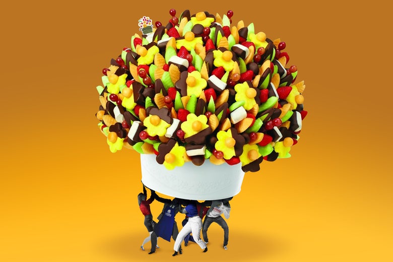 Tiny workers holding up a gigantic Edible Arrangement