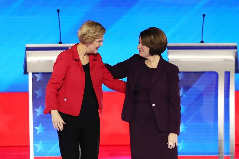 Warren and Klobuchar greet each other at the center of a debate stage.