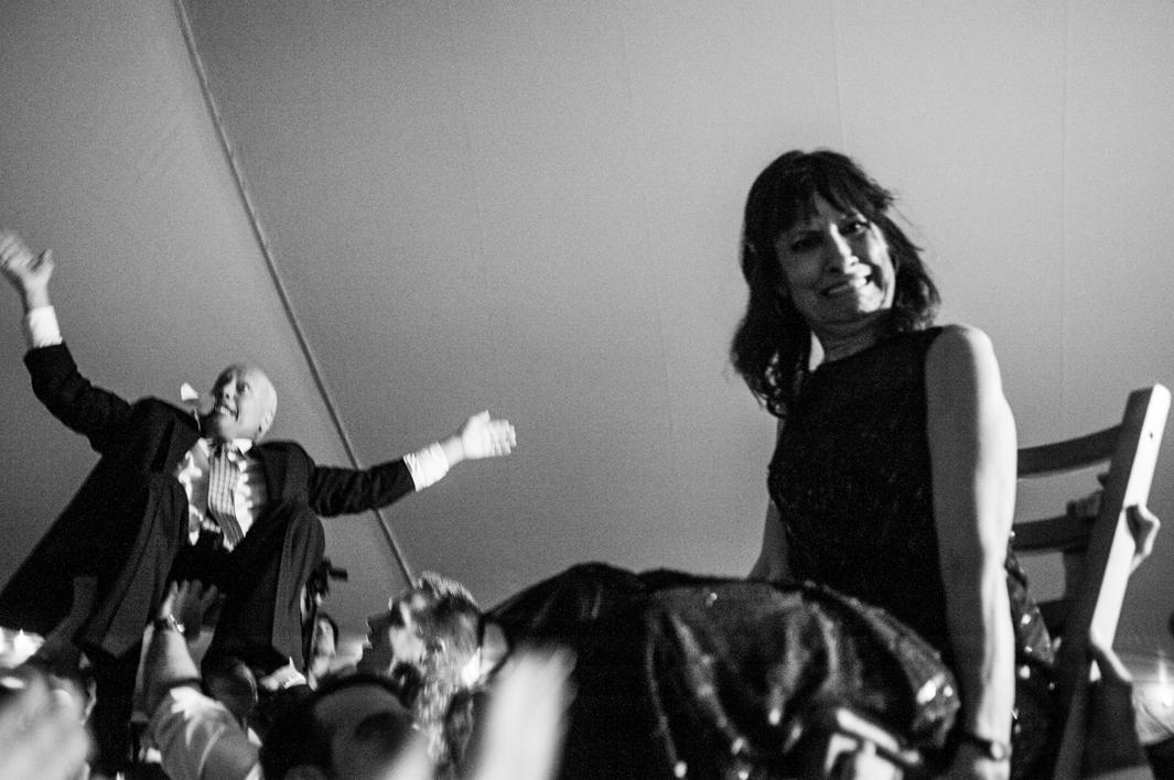 As part of Jewish tradition, Howard and Laurel Borowick, parents of the bride, are lifted in chairs during the Hora. Highland, New York. October, 2013.