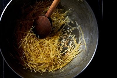 Angel hair pasta in the butter in the pot.