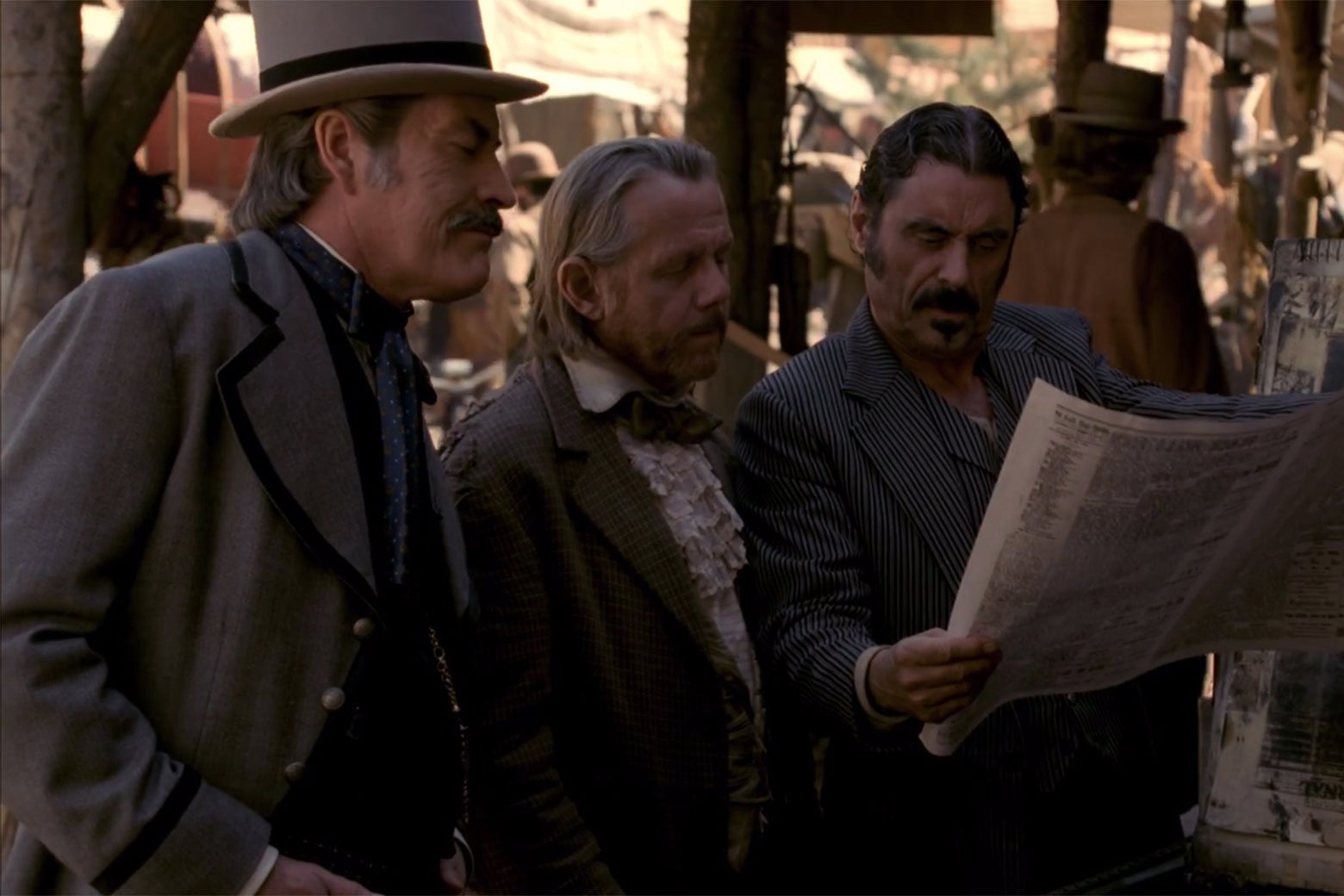 Cy Tolliver (Powers Boothe), E.B. Farnum (William Sanderson), and Al Swearengen (Ian McShane) read a copy of the Black Hills Weekly Pioneer in a still from Deadwood.