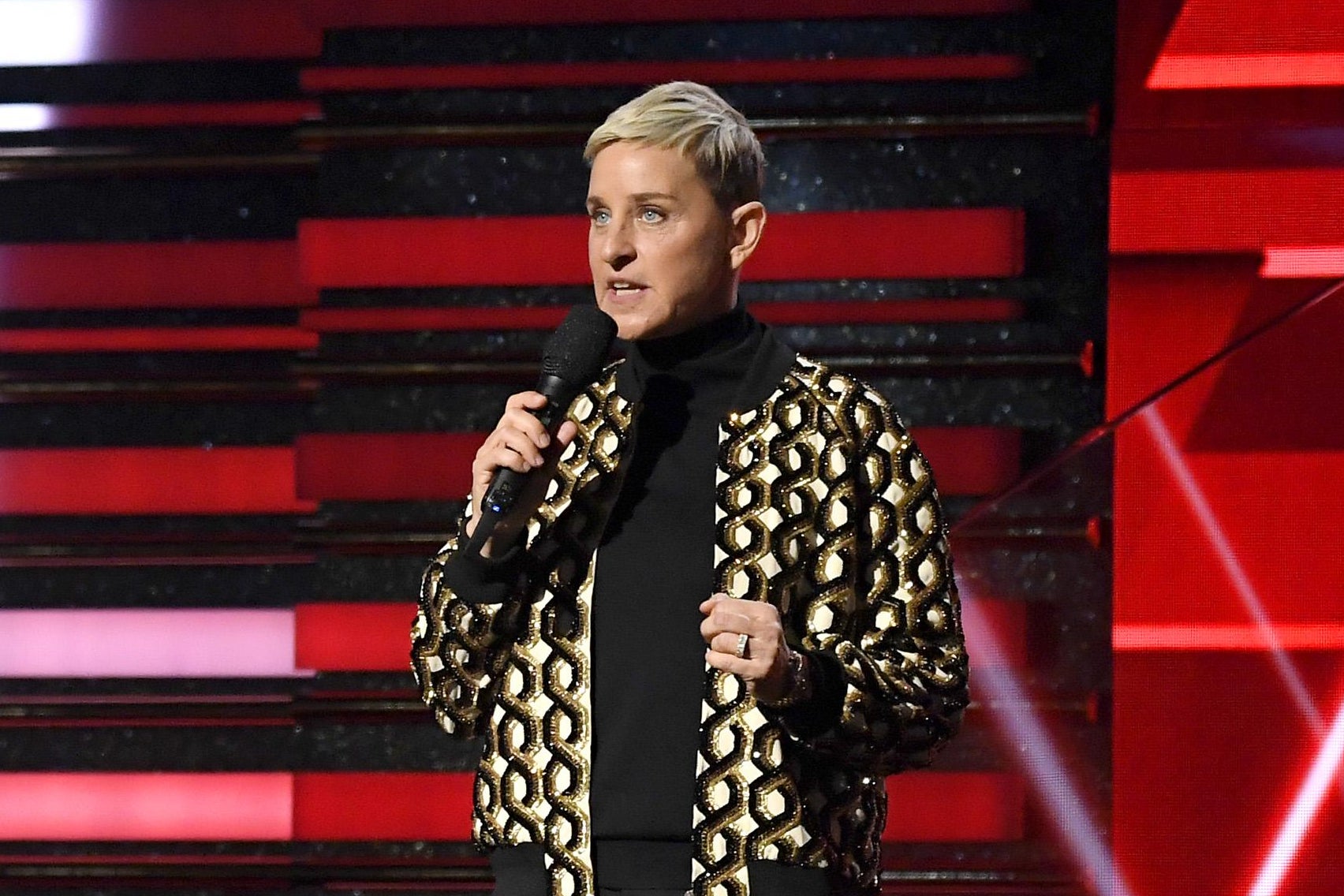 Ellen speaks onstage, holding a mic